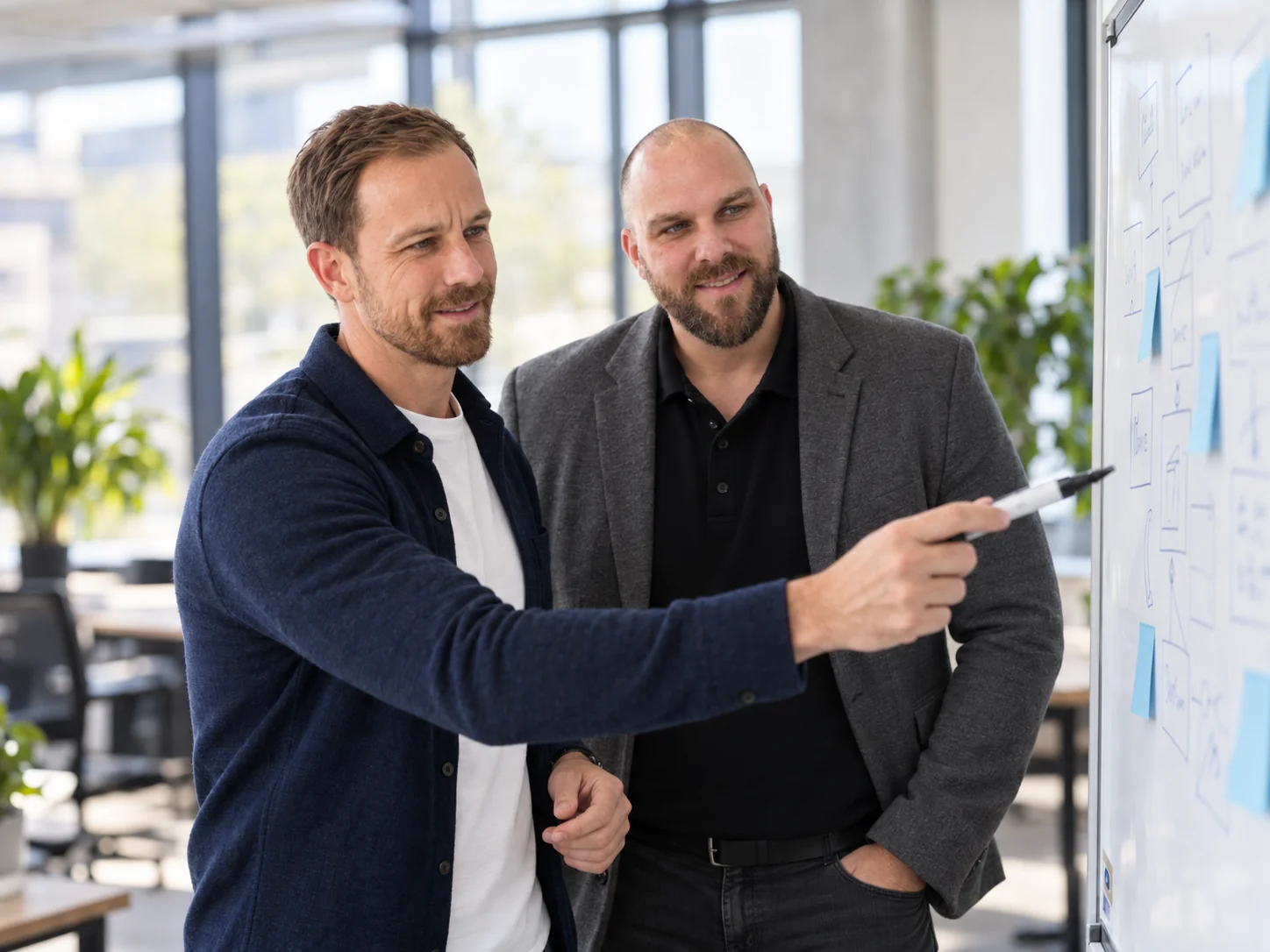 Frederic Baltes und David Rofall besprechen einen Ablauf am Whiteboard – KI-generiertes Symbolbild.