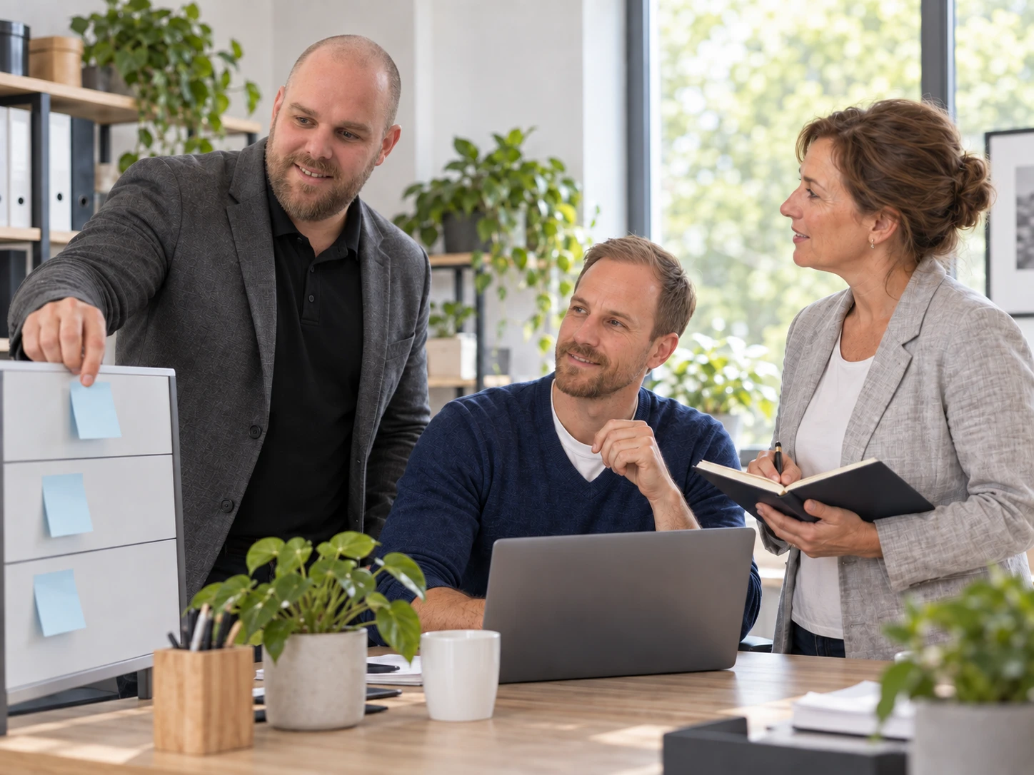 Freddy zeigt den nächsten Schritt am Board; David arbeitet am Laptop mit. KI-generiertes Symbolbild.